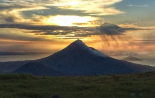 Momotombo Volcano at sunrise, orange clouds glowing behind the volcano from el hoyo backpacking trek