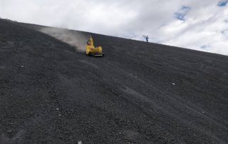 Volcano boarding down Cerro Negro with hand in air