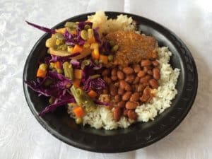 plate of beef steak, beans, rice, and salad, made by a homeowner receiving a roof from all hands and hearts