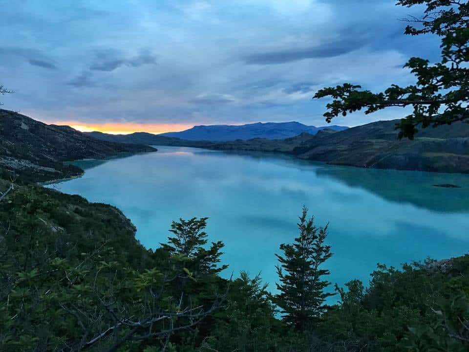 Turquoise sunrise reflecting on a turquoise lake, surrounded by trees