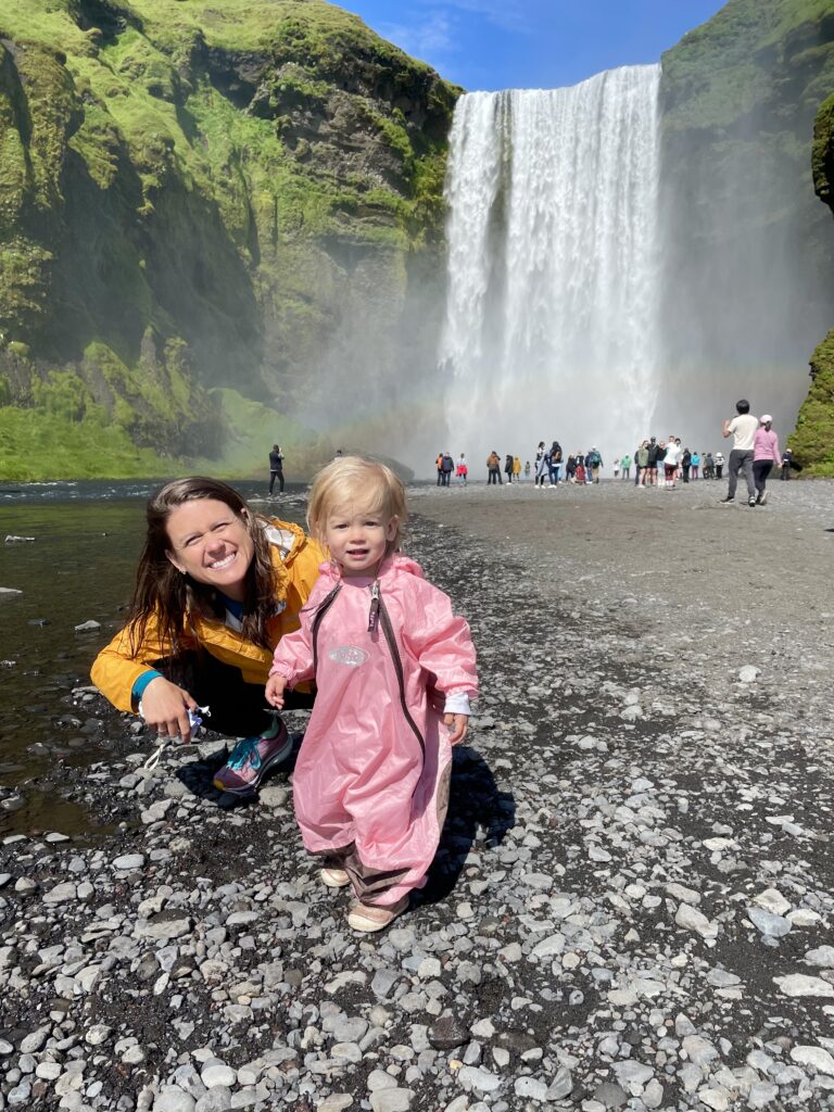 Iceland Skogafoss waterfall with toddler in rain suit