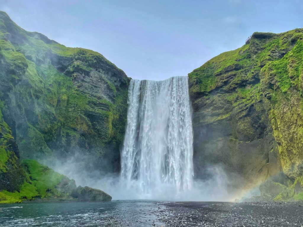 Skogafoss Waterfall with rainbow and green moss above. Best outdoor activities for toddlers in Iceland.