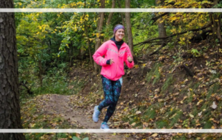 Runner in pink jacket on a woodsy trail