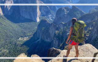 Backpacker with green backpack in Yosemite National park viewing mountains and trees.