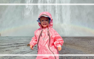Toddler Travel Tips toddler in rain suit in front of rainbow waterfall