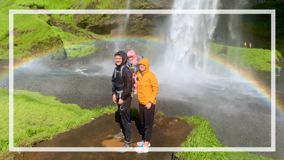 Iceland family vacation in front of waterfall and rainbow.