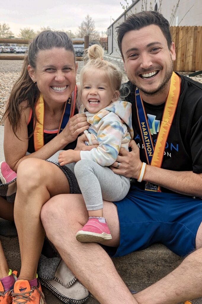 2 parent marathon runners with medals and toddler